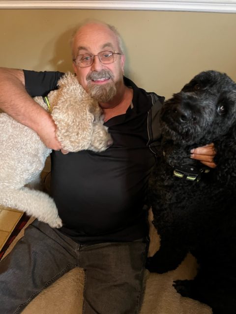 A man holds two dogs.