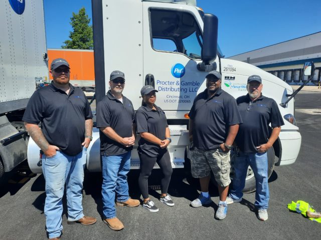 Five men stand in front of a truck.