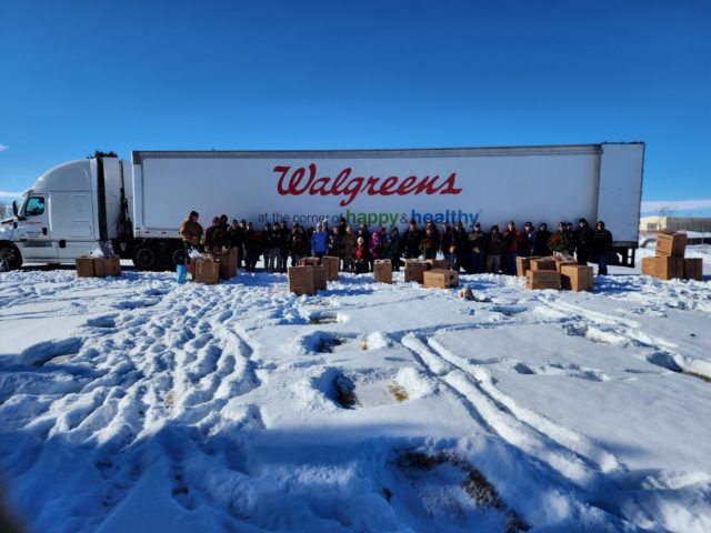 A crowd of people stand in front of a Walgreens truck