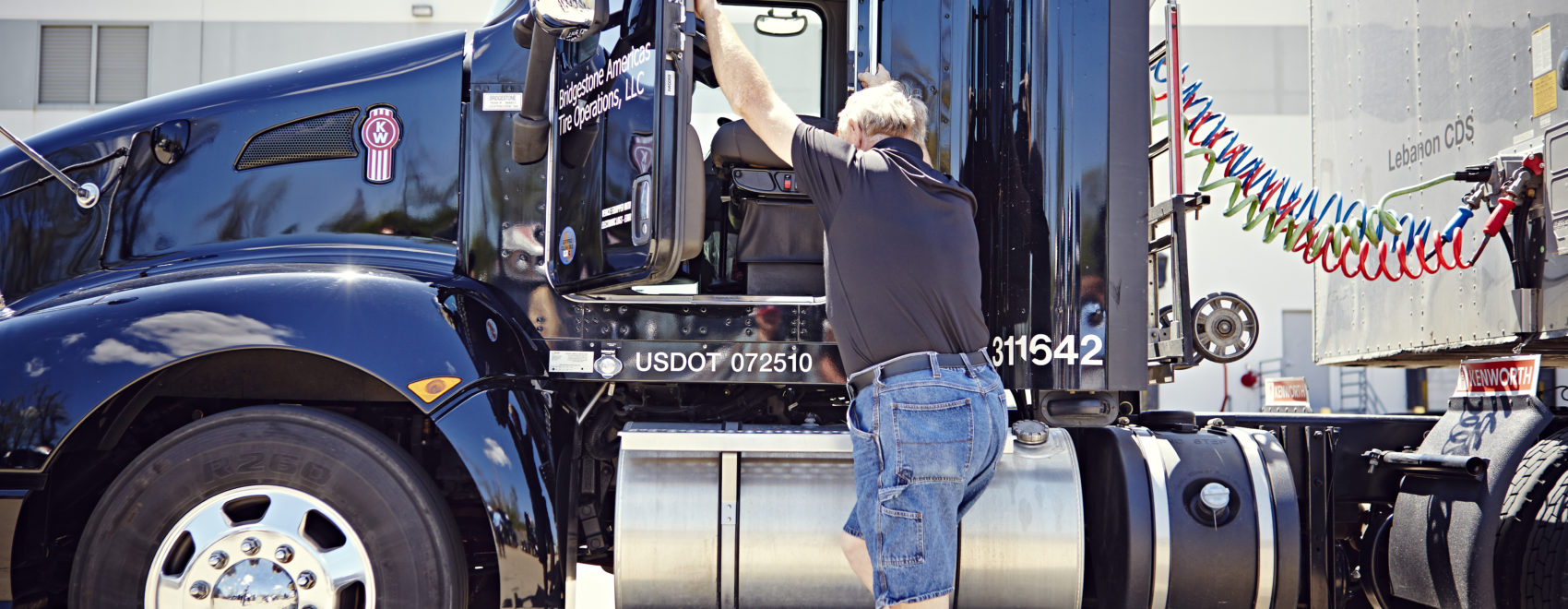A man climbs into the cab of a truck.