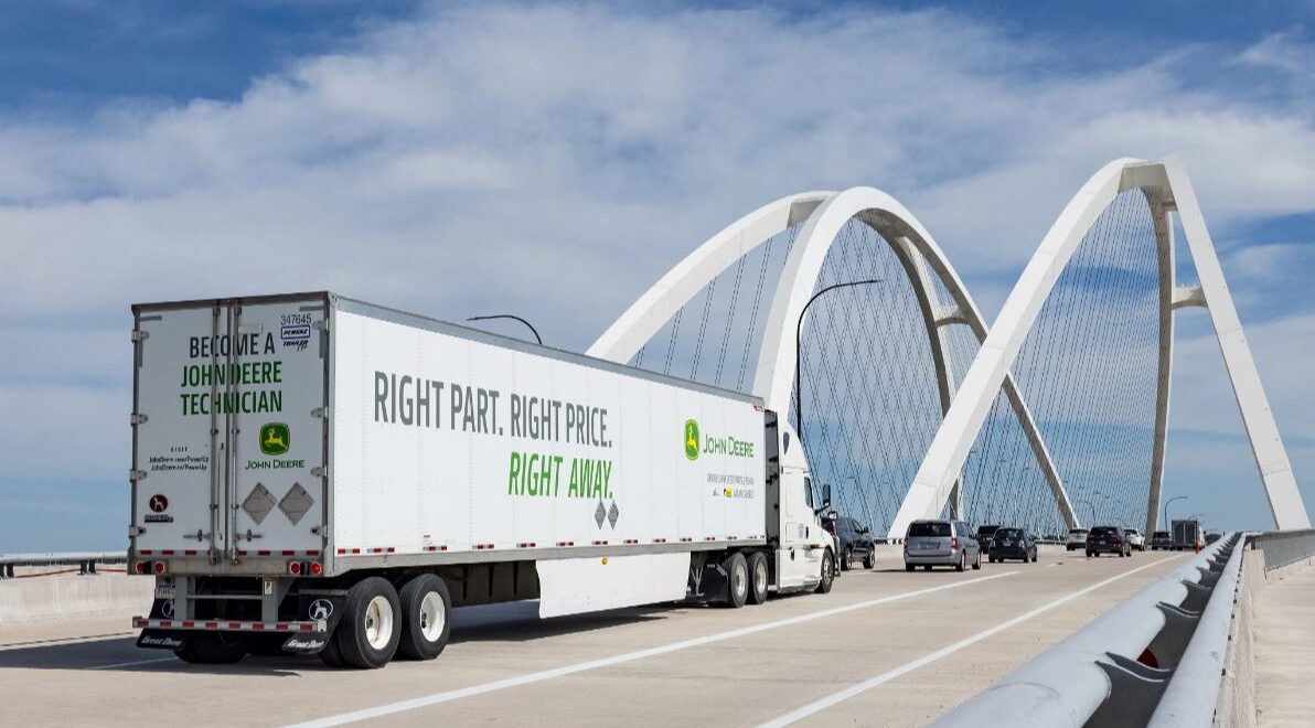A John Deere truck drives over a bridge.