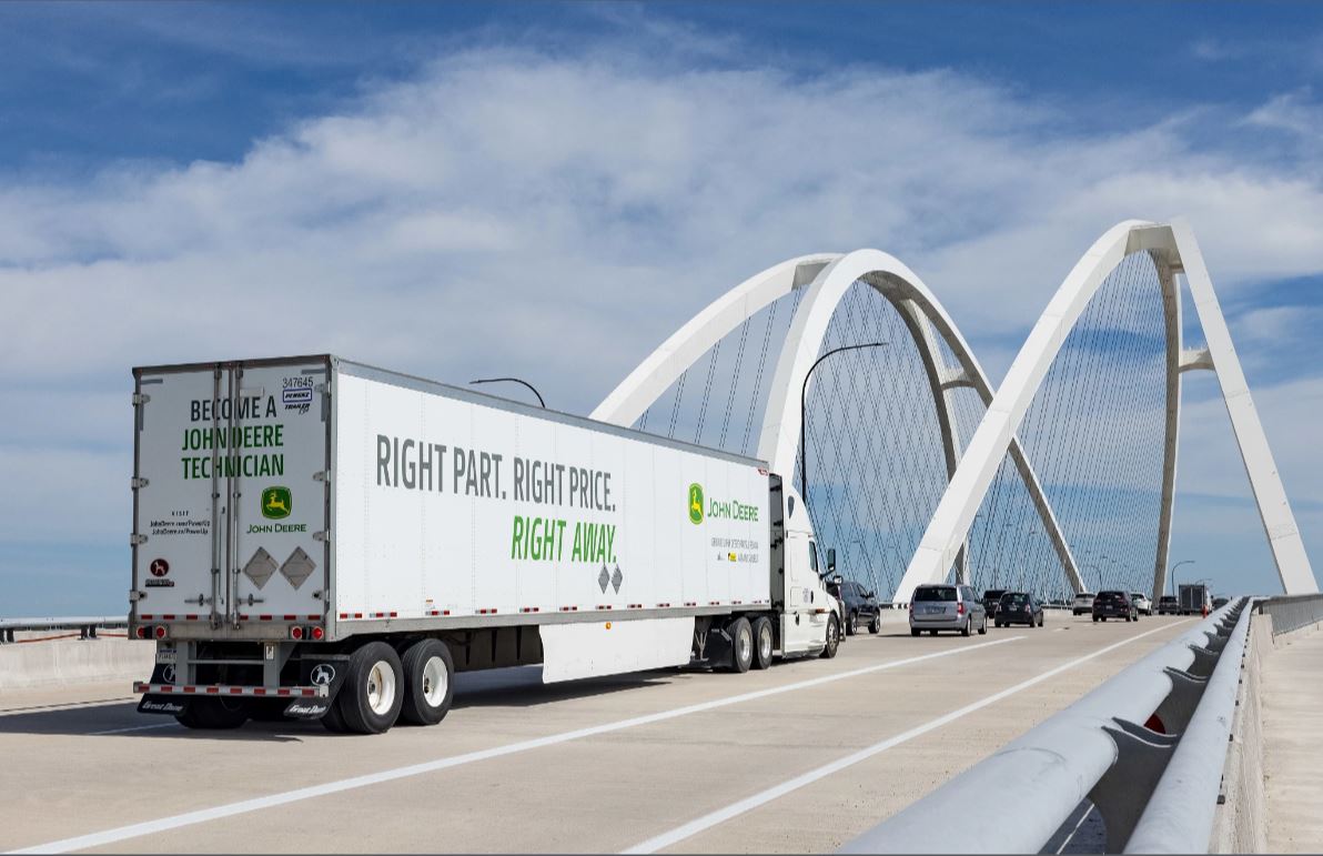 A John Deere truck drives over a bridge.