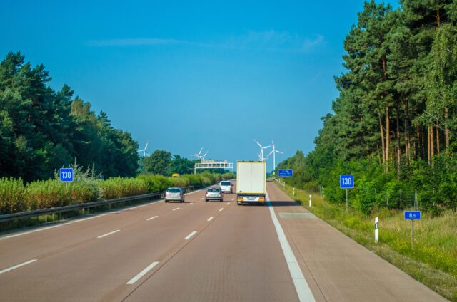 A truck travels down a highway on a summer day.