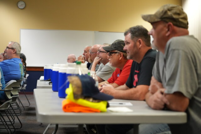 A row of men watch a presentation