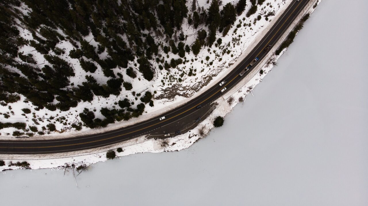 Cars drive on a road surrounded by a winter landscape
