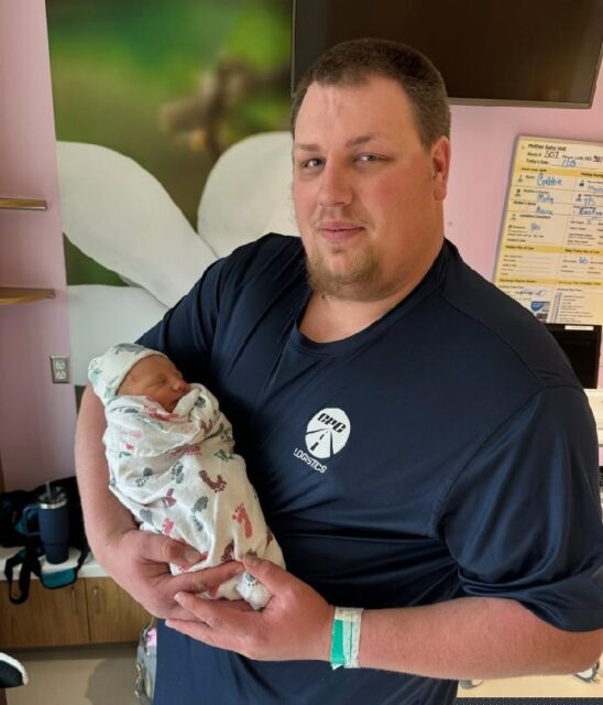 Tyler Coots holds his newborn baby.