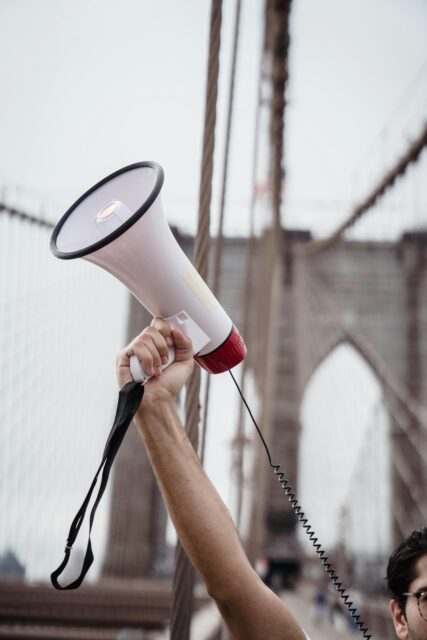 A person holds a megaphone in the air