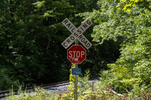 A "Railroad Crossing" sign near a railroad in a forest