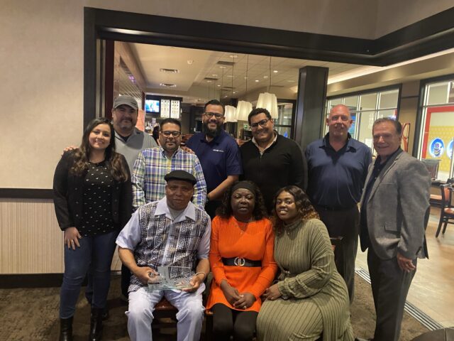 Back row: Administrative Assistant Melissa Milla, Associate Logistics Manager Luis Ronceros, Division Manager Allan Flores, Operations Manager Alex Campos, Associate Logistics Manager Fady Aly, Safety Supervisor Carmen Parisio, and Safety Manager Joe Cosenza. Front row: Robert Ross, his wife Persis Ross, and daughter Nourine Robinson.