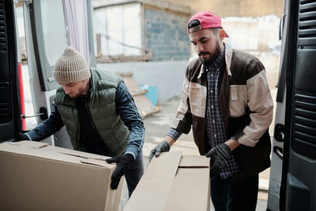 Two men lift boxes from the back of a truck