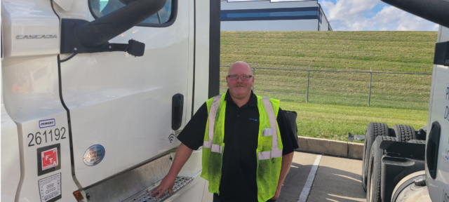 Ryan Baker stands near the door of a semi-truck.