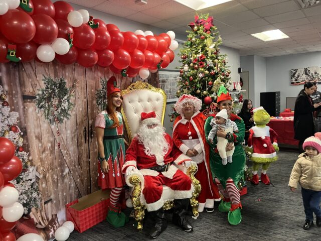 Santa sits on a throne surrounded by elves