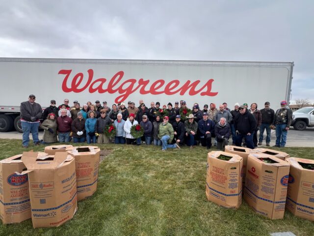 A group of people stands in front of a Walgreens truck