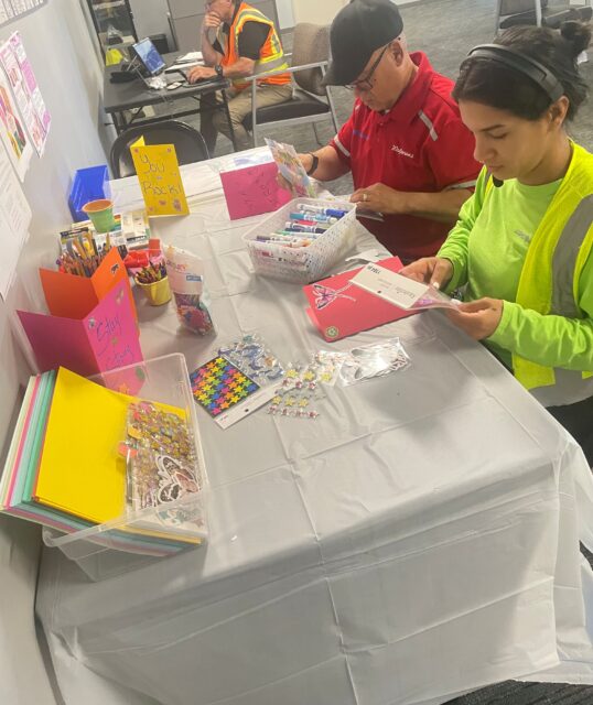 A man and a woman sit at a table decorating greeting cards