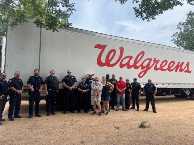 People stand in front of a Walgreens truck.
