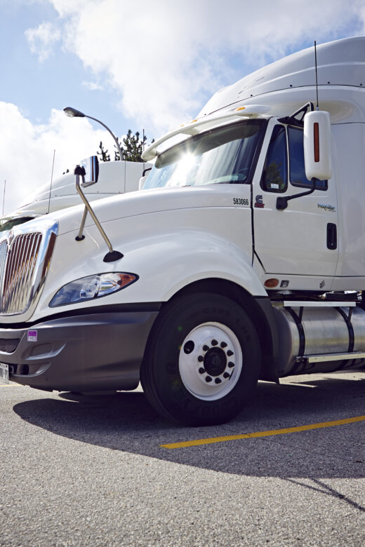 A row of semi-trucks parked in a parking lot.