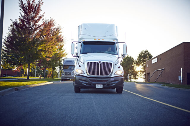 A semi-truck drives down a road.
