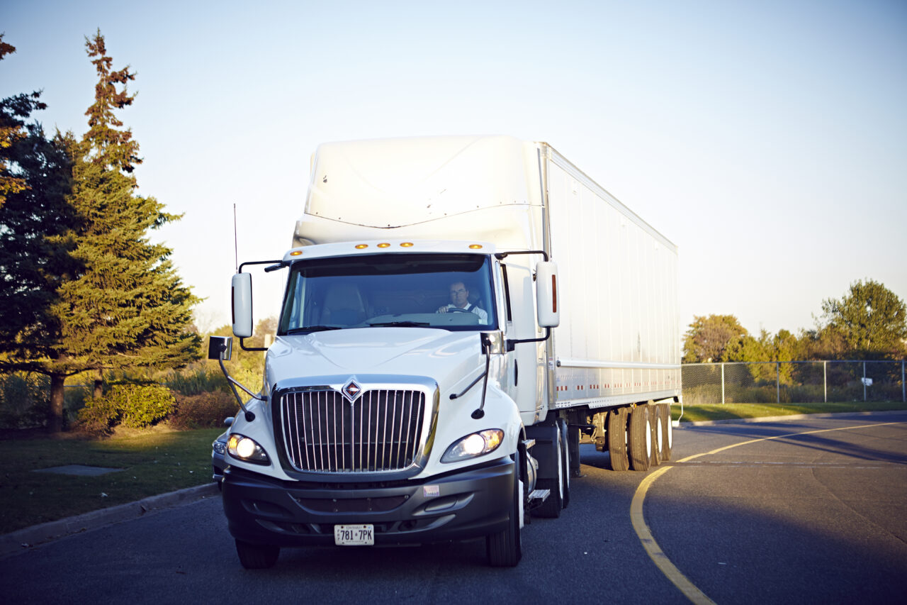 A semi-truck drives down a curved road.