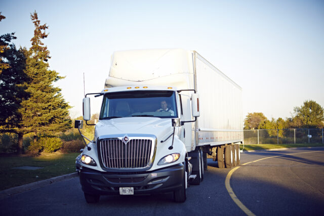 A semi-truck drives down a curved road.